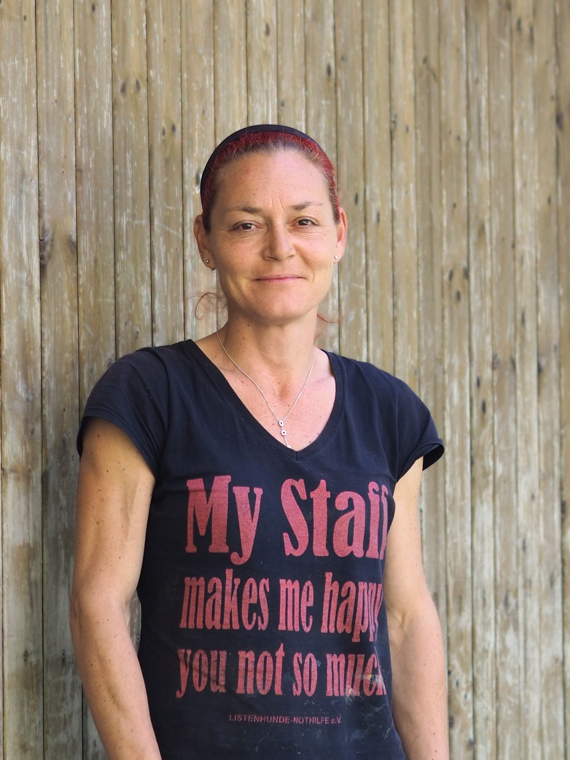 Frau mit roten geschlossenen Haaren und einem schwarzen Tshirt mit rotem Aufdruck